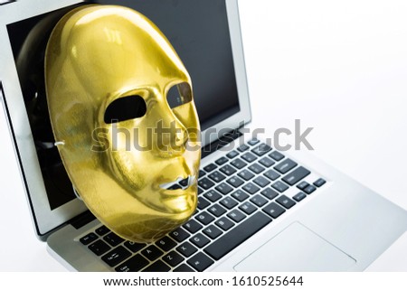 Golden mask on laptop against white background, as a symbol of  hacker attack.