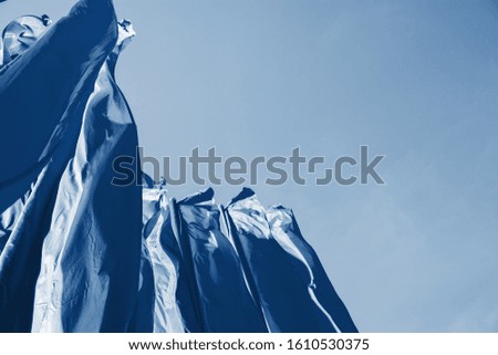 dark blue big street flags fluttering in the wind, pointing up at the clear, cloudless blue sky