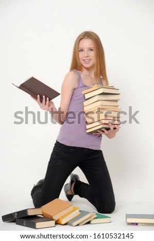 A woman with a smile on her face holding on to a stack of books