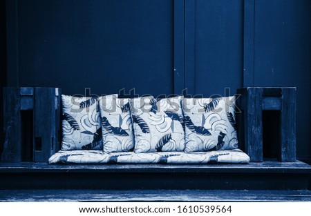 an unusual street extravagant sofa made of wooden planks and pillows with exotic pattern in blue tones, the interiors of the cafe