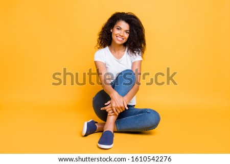 Photo of cheerful cute nice fascinating gorgeous girl wearing jeans denim smiling toothily beaming sitting isolated over vivid yellow color background