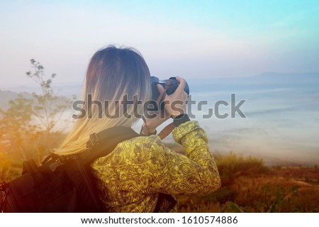 Backpack young woman tourist photographer taking picture in the morning scene with fog and the mountain