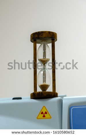 Hourglass over radiation sign on a light background