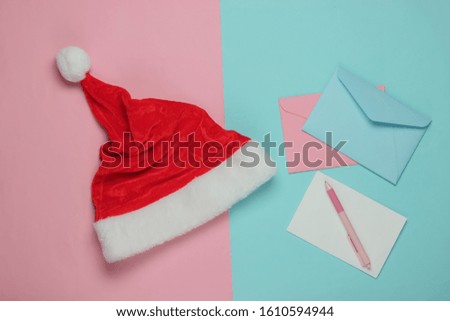 Letter to Santa. Santa hat, envelope with a letter and pen on pink blue background. Christmas Flat lay. Top view