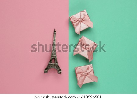 Gift boxex with bow, statuette of the Eiffel Tower on pink blue pastel background. Shopping in Paris, souvenirs. Top view