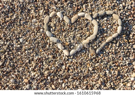 Two hearts laid out of pebbles on the beach. The concept of people who love each other. Valentine's day gift.