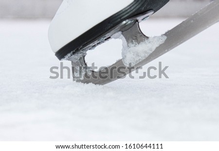 The figure skates on the leg are stuck with teeth in the ice.