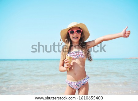 Cute little girl has fun on the beach. Summertime concept.