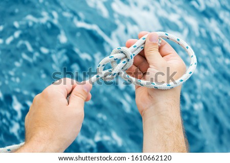 Hands making a bowline nautical knot Royalty-Free Stock Photo #1610662120