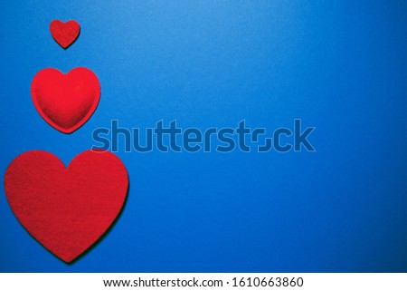 Decorative felt hearts on blue background. Abstract backdrop with copy space. Love and romance theme. Valentine day theme. Flat lay style