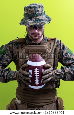 solder holding american football ball ready for game concept of peace green background