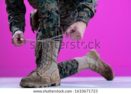 close up of soldier hands while tying boot laces  purple background