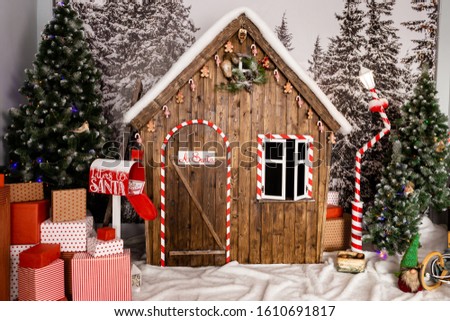 New Year's photo zone with snow near a wooden toy house. Christmas decor: toys, Christmas trees, garland, Concept of festive mood, picture for postcard.