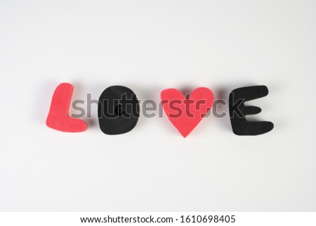 The inscription "Love" of plastic letters in pink and black on a white background, the concept for Valentine's Day, wedding, birthday and other holidays, the view from the top.
