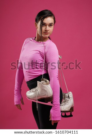 Portrait of sporty young athletic woman standing with skates on pink background