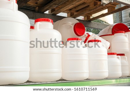 White plastic cans with red lids on a rack stillage. Domestic tanks for drinking water.