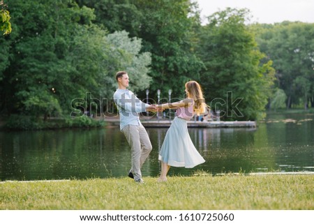 A romantic couple in love holding hands and spinning on the shore of the lake. Valentine's day