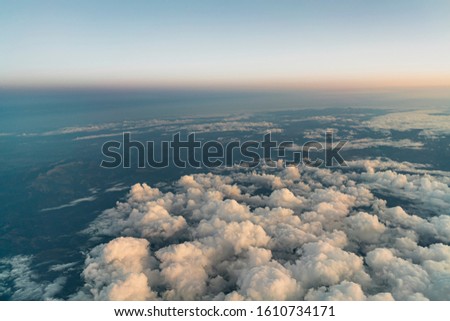 View from an airplane flying above clouds, at dawn in the morning