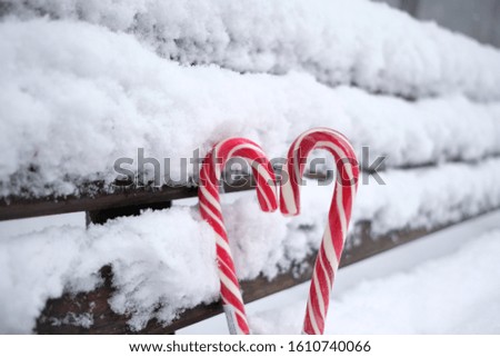 Peppermint lollipops in heart shape in the snow.in the open space
