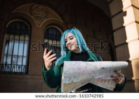 Smiling female tourist checking location on smartphone