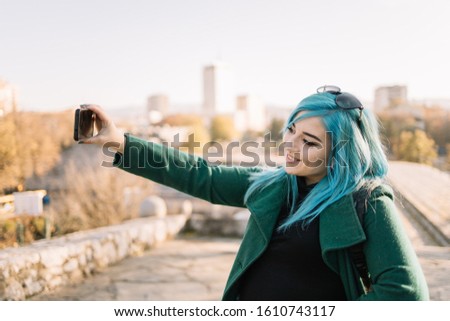 Girl smiling and taking selfie using smartphone