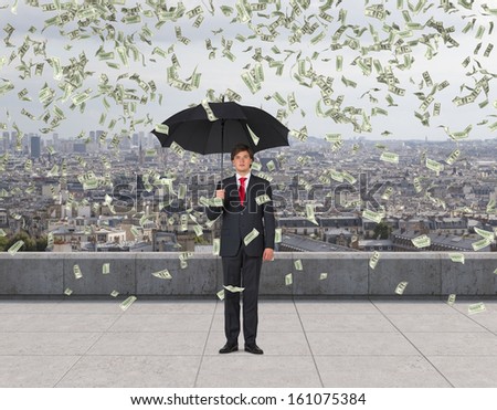 Businessman standing on a roof in the rain of money.