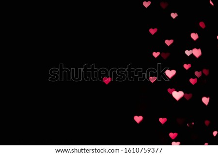 Abstract blur with pink and red bokeh hearts on a black backdrop for a wedding card or Valentines day