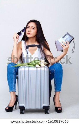 Travel concept. Studio portrait of pretty young asian woman holding passport and glass with suitcase and thinking about something. Isolated on white background, tourism, summer holidays and vacation