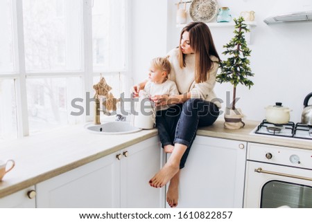 Mom feeds her daughter from a spoon. Family in the bright kitchen. 