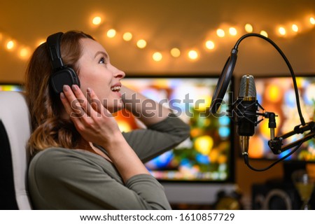 A girl radio host in a cozy atmosphere broadcasts with a studio microphone. Stream, live broadcast, blogging. Pastes