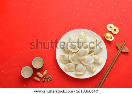 Traditional Chinese food dumplings on the red background.Translation of text appear in image: Blessing and treasure.