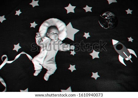 little boy baby sleeping in a suit of the astronaut on the background of the starry sky with stars and a space ship. View top, flat lay. Monochrome photography with 3D glitch effect