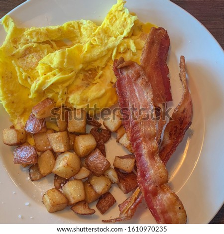 Close-up picture of a traditional American breakfast. Scramble eggs, bacon and country style potatoes.