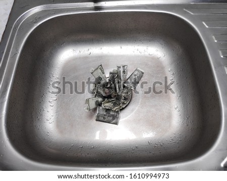 Money in Sink/ money being flushed down the sink, a metaphor for wasting cash. 
To describe the financial or business that is losing or bankrupt.