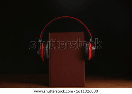 Headphones and book on wooden table against black background