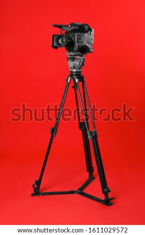 Modern professional video camera on red background