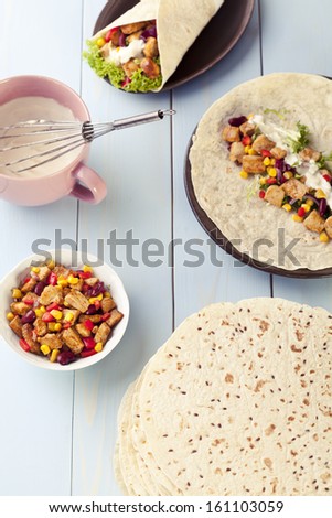 tortilla wraps with meat and vegetables on blue wood board