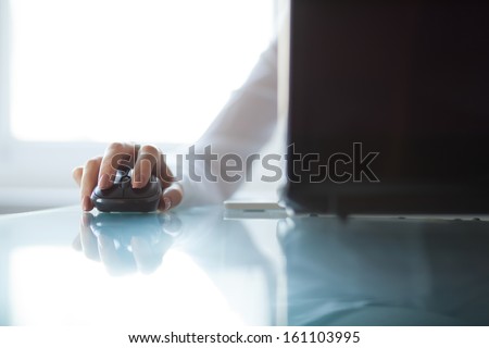 Woman's hand using cordless mouse on glass table Royalty-Free Stock Photo #161103995