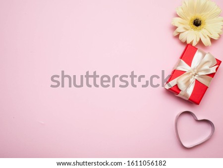 blank for designers. pink background. against the background of a white gerbera, a red box with a gift and a heart