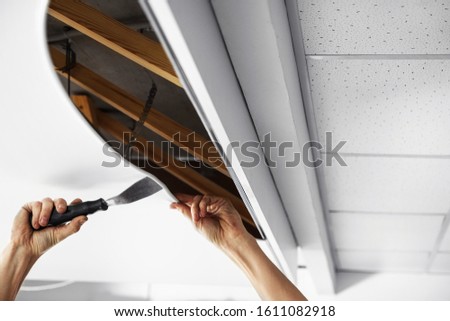 Repairman installing white stretch ceiling in room, closeup