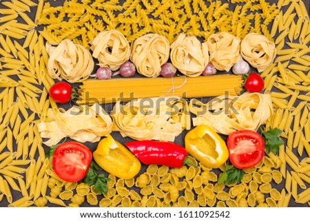 Various uncooked pasta with vegetables tomatoes, yellow and red peppers, garlic, parsley. Organic food  on black background. Top view 
