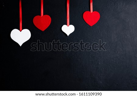 Four decorative hearts of different sizes and colors. Decorative hearts tied on a red rope. The horizontal location. Copy space