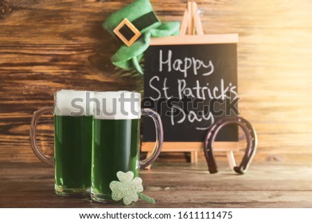 Mugs of green beer for St. Patrick's Day on wooden table