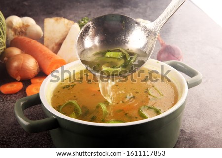 Broth with carrots, onions various fresh vegetables in a pot - colorful fresh clear spring soup. Rural kitchen scenery vegetarian bouillon