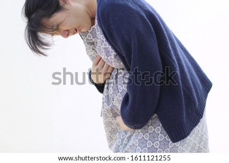 a pregnant woman put her hand on her chest due to gastroesophageal reflux disease Royalty-Free Stock Photo #1611121255
