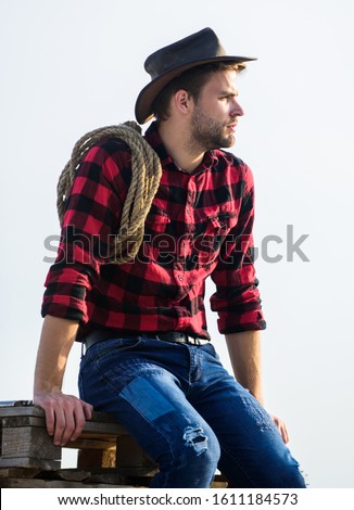 Thoughtful farmer thinking about business. Ranch worker. Eco farm. Farming concept. Handsome man in hat and rustic style outfit. Keep ranch. Life at ranch. Cowboy with lasso rope sky background. Royalty-Free Stock Photo #1611184573