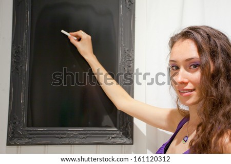 Young attractive woman typing on blackboard, teacher or student