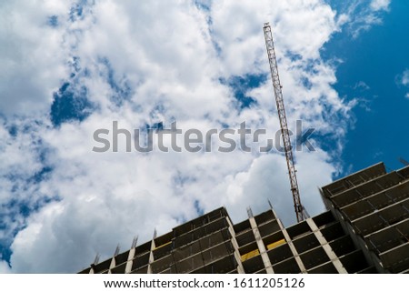 Photo of a multi-storey building under construction. Construction of a residential skyscraper. Background image of the process of building a house with cranes.