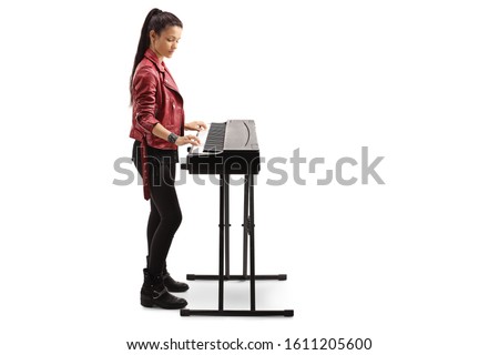 Full length profile shot of a young woman playing a digital piano isolated on white background
