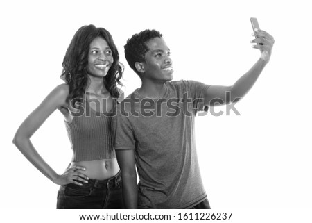 Happy African sister and brother taking selfie with mobile phone together with brother taking the picture